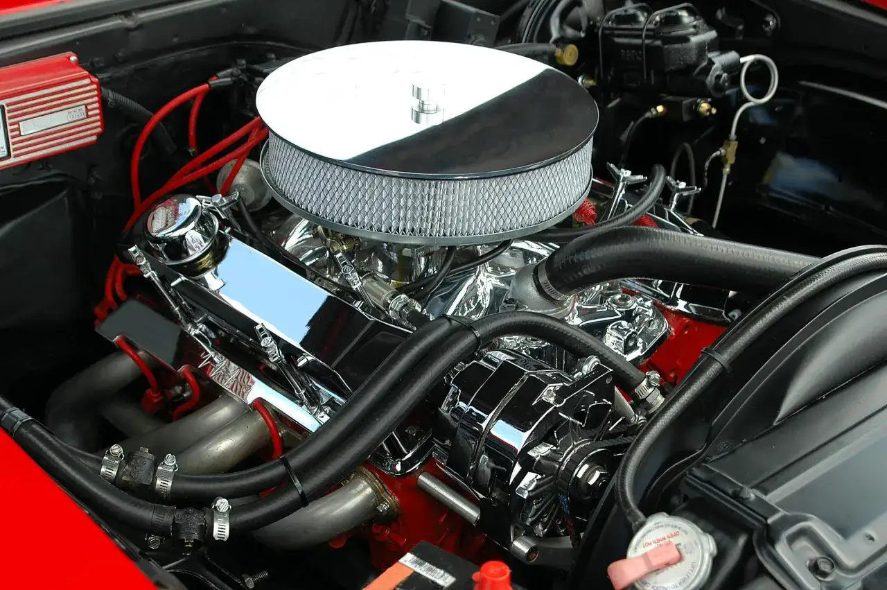 Błyszczący silnik V8 z chromowanymi elementami i czerwonymi przewodami zapłonowymi. Ten potężny motor, gotowy do pokonania wielu kilometrów, to kwintesencja mocy.