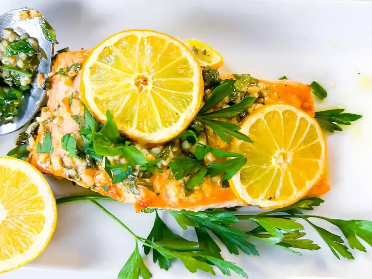 Filet de saumon cuit, garni de rondelles de citron, persil frais et d'une sauce aux herbes. Une recette saumon parfaite pour un repas léger.