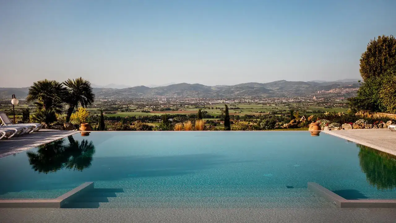 Piscina a sfioro con vista panoramica su colline e città. Ideale per agriturismi con piscina che cercano relax e bellezza.
