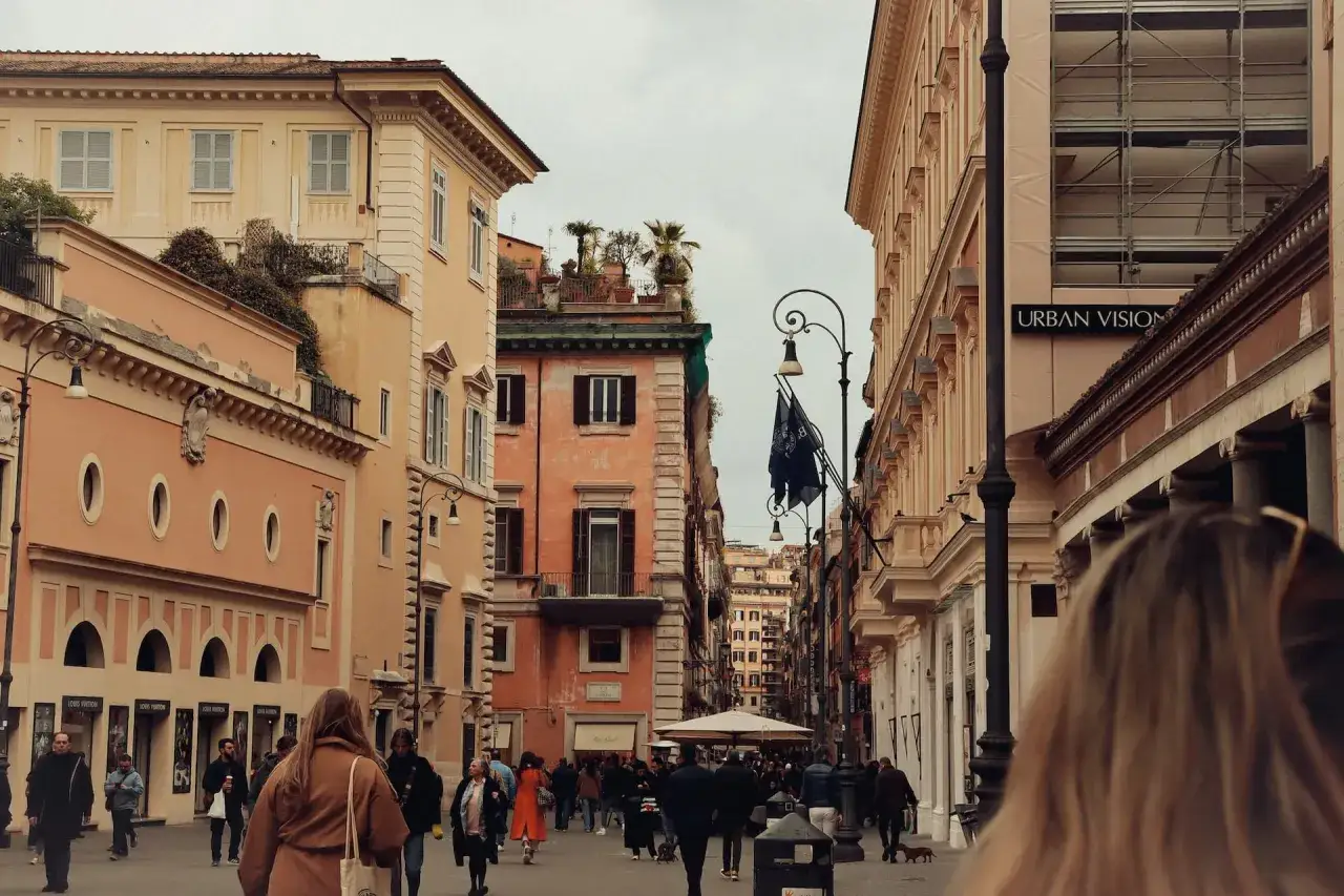 Une rue animée à Rome en novembre, avec des bâtiments aux couleurs chaudes et des passants.