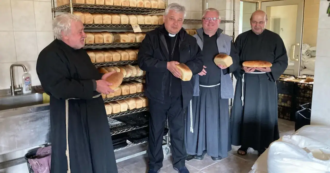 Jałmużnik papieski i jego pomocnicy prezentują świeżo upieczony chleb, symbol dobroci i wsparcia dla potrzebujących.