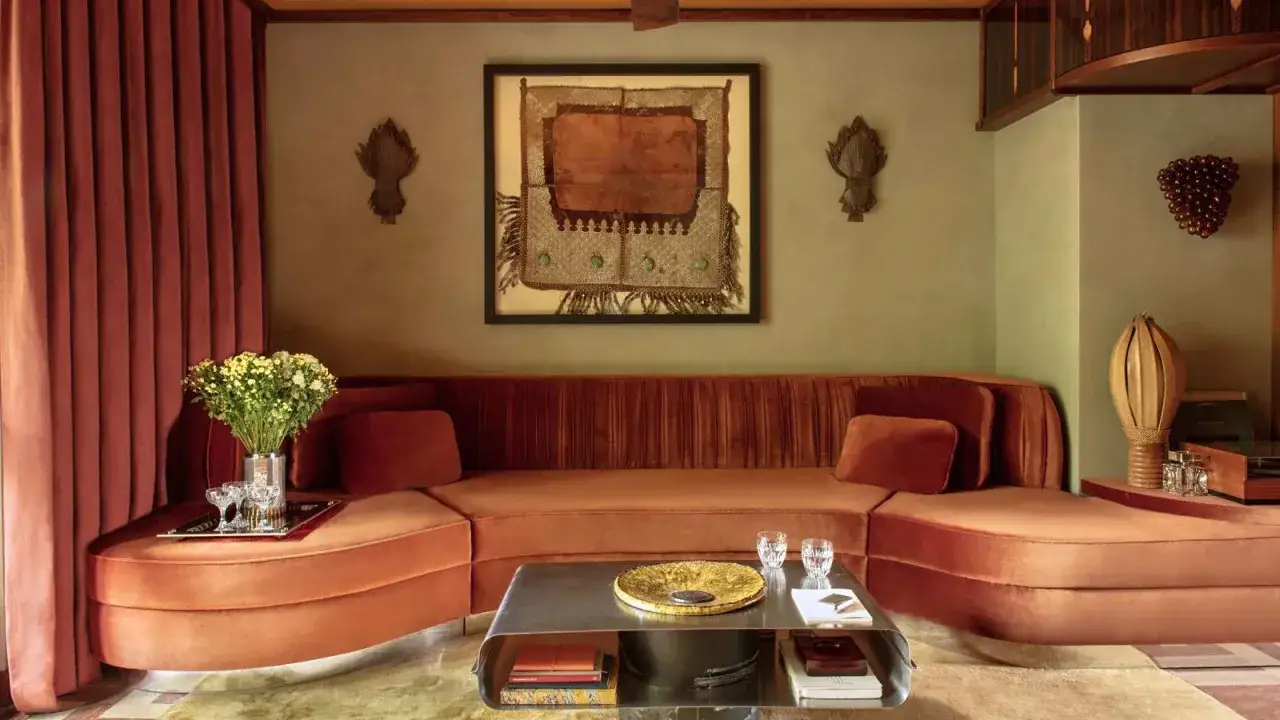 Salon cosy avec canapé arrondi orange, rideaux assortis, et une œuvre d'art ethnique au mur. Une belle deco salon.