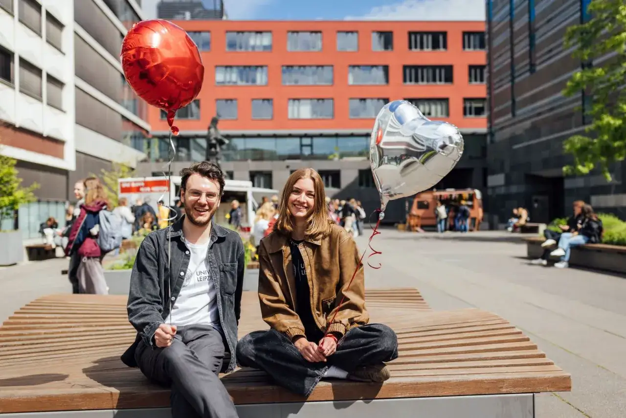 Glückliche Studierende mit Ballons vor der Uni Leipzig. Ein toller Ort für ein berufsbegleitendes Studium in Leipzig.
