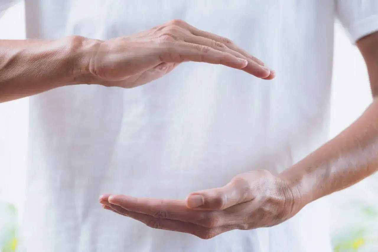 Dłonie w geście otaczania, symbolizujące energię. Czy reiki jest niebezpieczne? To pytanie nurtuje wiele osób szukających ukojenia.