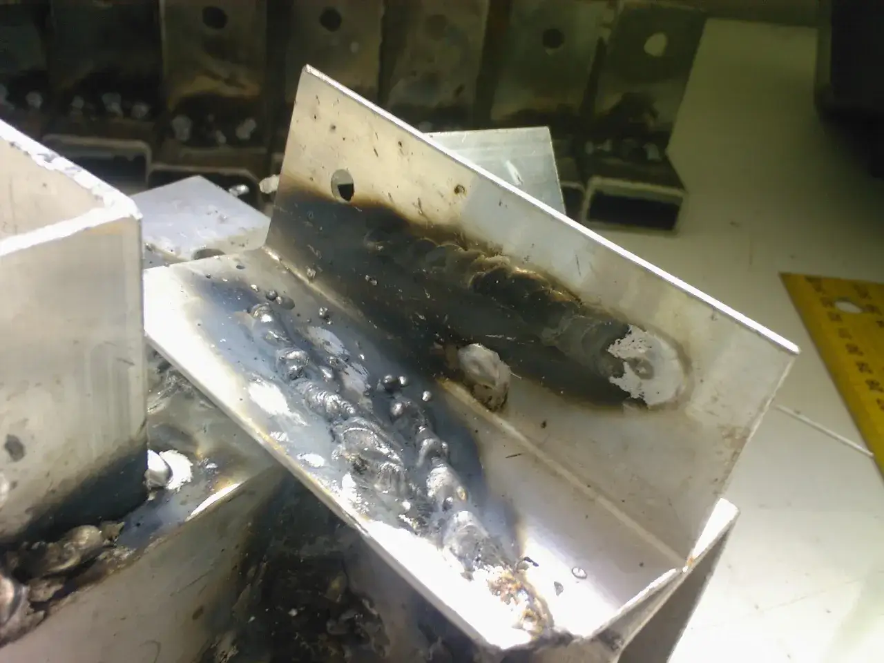 Fragmenty aluminium po spawaniu migomatem. Widoczne ślady spoin i naloty.