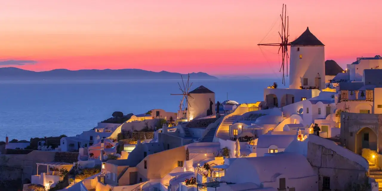 Zachód słońca na Santorini. Idealna grecja pogoda lipiec, białe domki i wiatraki nad morzem.