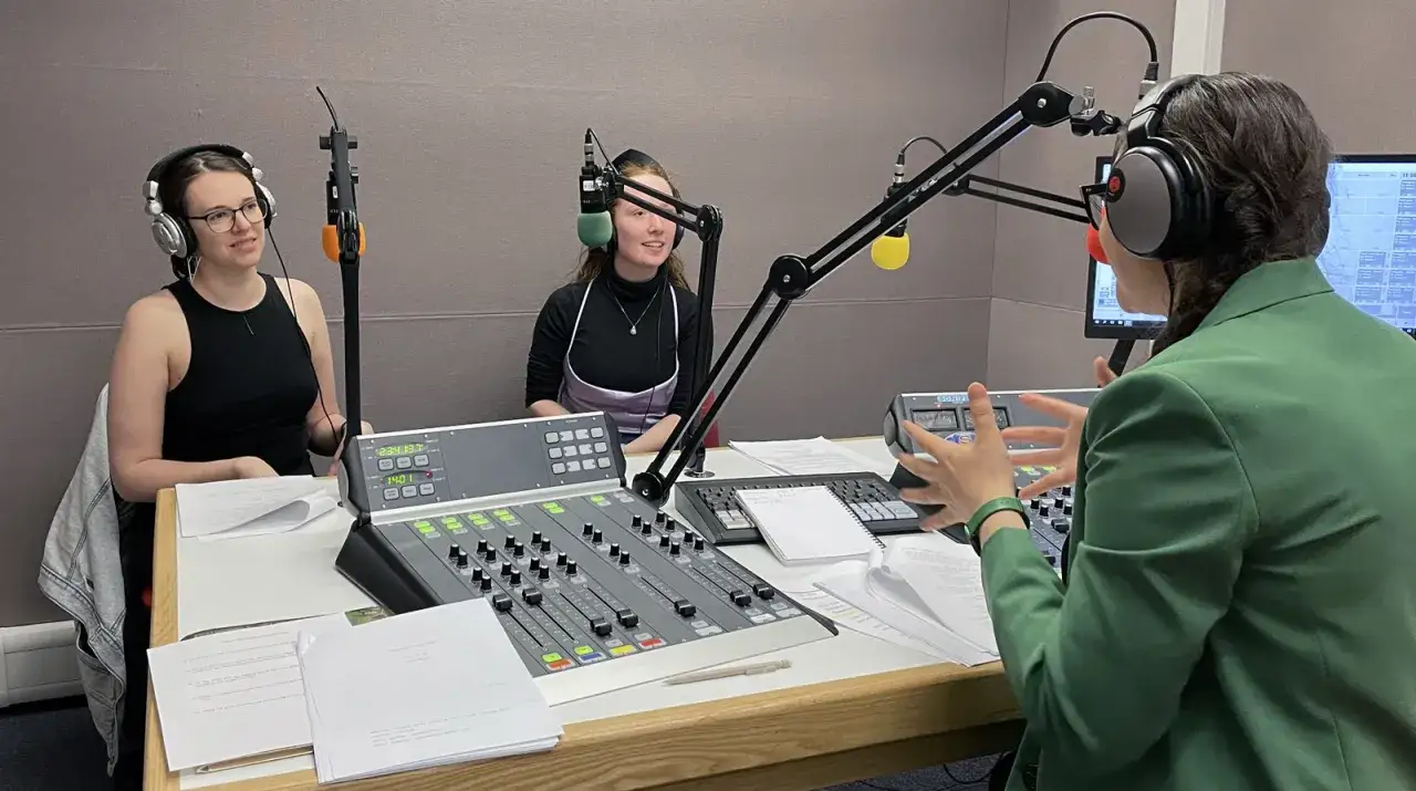 Trzy osoby w słuchawkach przy konsoli radiowej. Jedna z nich, w zielonej marynarce, gestykuluje, jakby tłumaczyła, dlaczego reżyser zdecydował się na dubbingowanie głosu znanej aktorki.