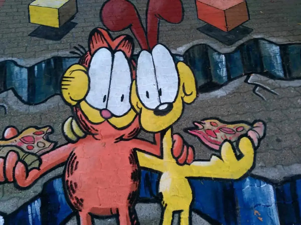 Garfield i Odie jedzą pizzę. Inspiracja, jak zrobić mural na kartce, z kreskówkowymi postaciami i blokami.