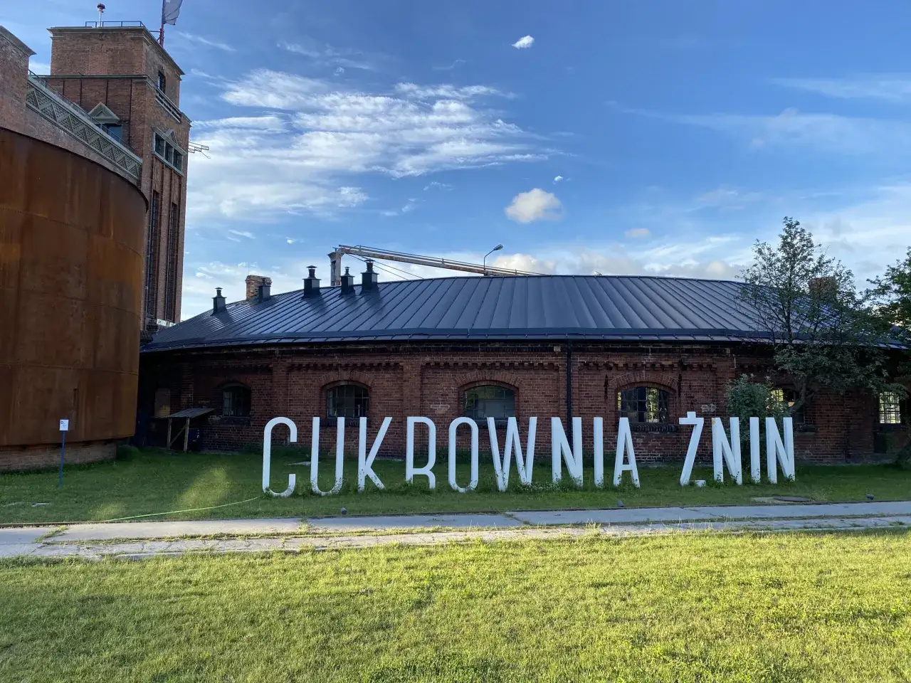 Cukrownia Żnin – ciekawe miejsce, które oferuje atrakcje dla dzieci. W tle ceglane budynki i błękitne niebo.
