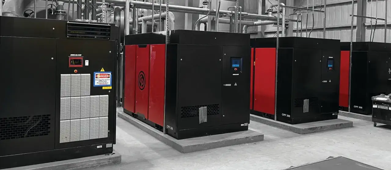 Varios compresores Alfaro negros y rojos, con tuberías industriales al fondo.