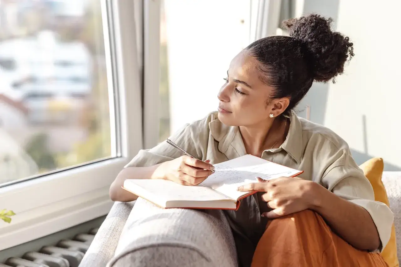Mujer reflexiona y escribe en un diario, explorando cómo saber si tengo un don espiritual.