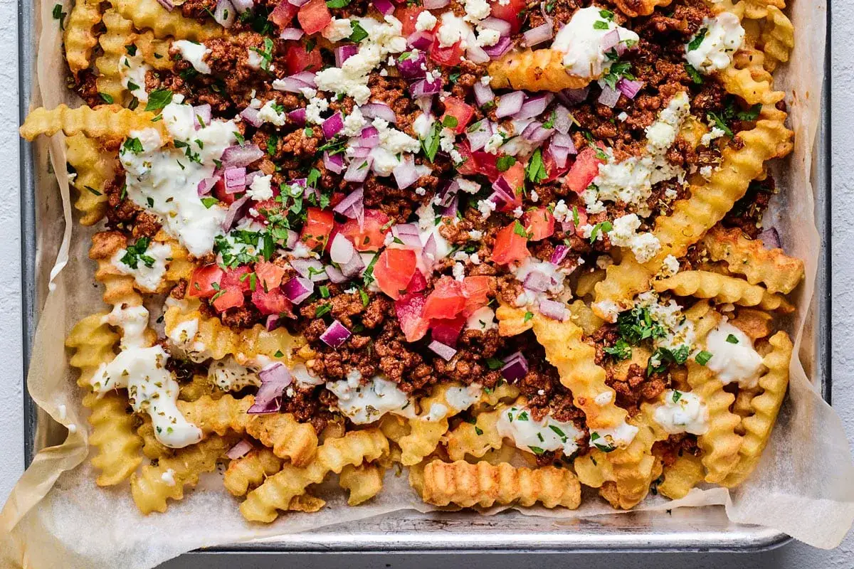 Krispiga pommes frites toppade med k&ouml;ttf&auml;rs, tomat, r&ouml;dl&ouml;k, fetaost och en kr&auml;mig s&aring;s. En riktig fest f&ouml;r smakl&ouml;karna!