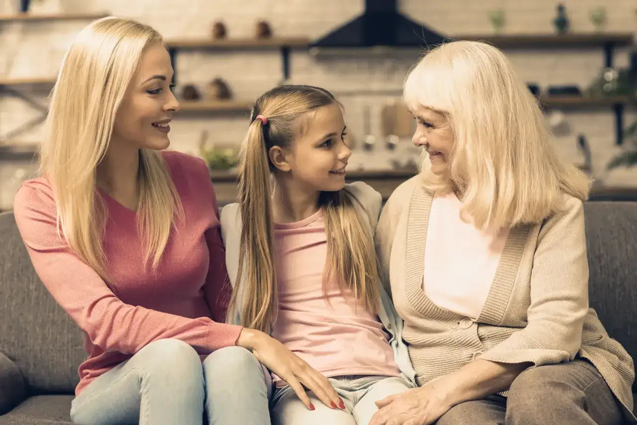 Trzy pokolenia kobiet: babcia, mama i wnuczka, siedzą blisko siebie, uśmiechając się. Ile razy można dać darowiznę dziecku? Tyle, ile razy serce podpowie.