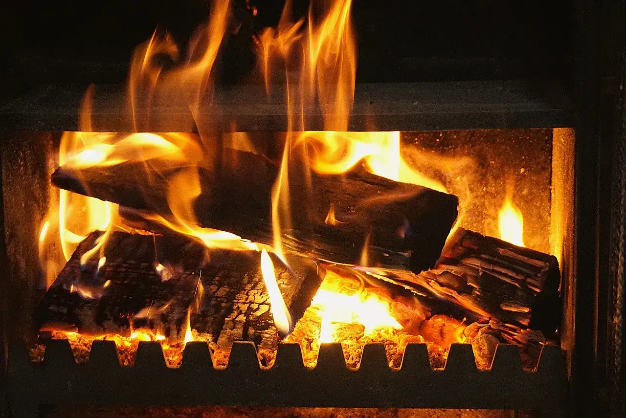 Glühende Holzscheite im Kamin, die Flammen tanzen. Ab wann brennt Holz? Sobald es die Zündtemperatur erreicht hat, beginnt es zu brennen und spendet Wärme.