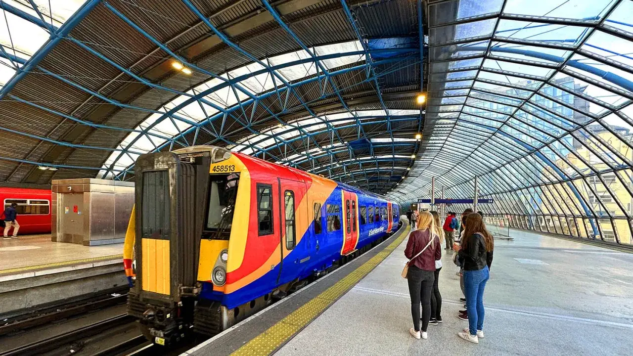 F&auml;rgglatt t&aring;g redo f&ouml;r resan till London. Folk v&auml;ntar p&aring; perrongen under den glaskl&auml;dda takkonstruktionen.