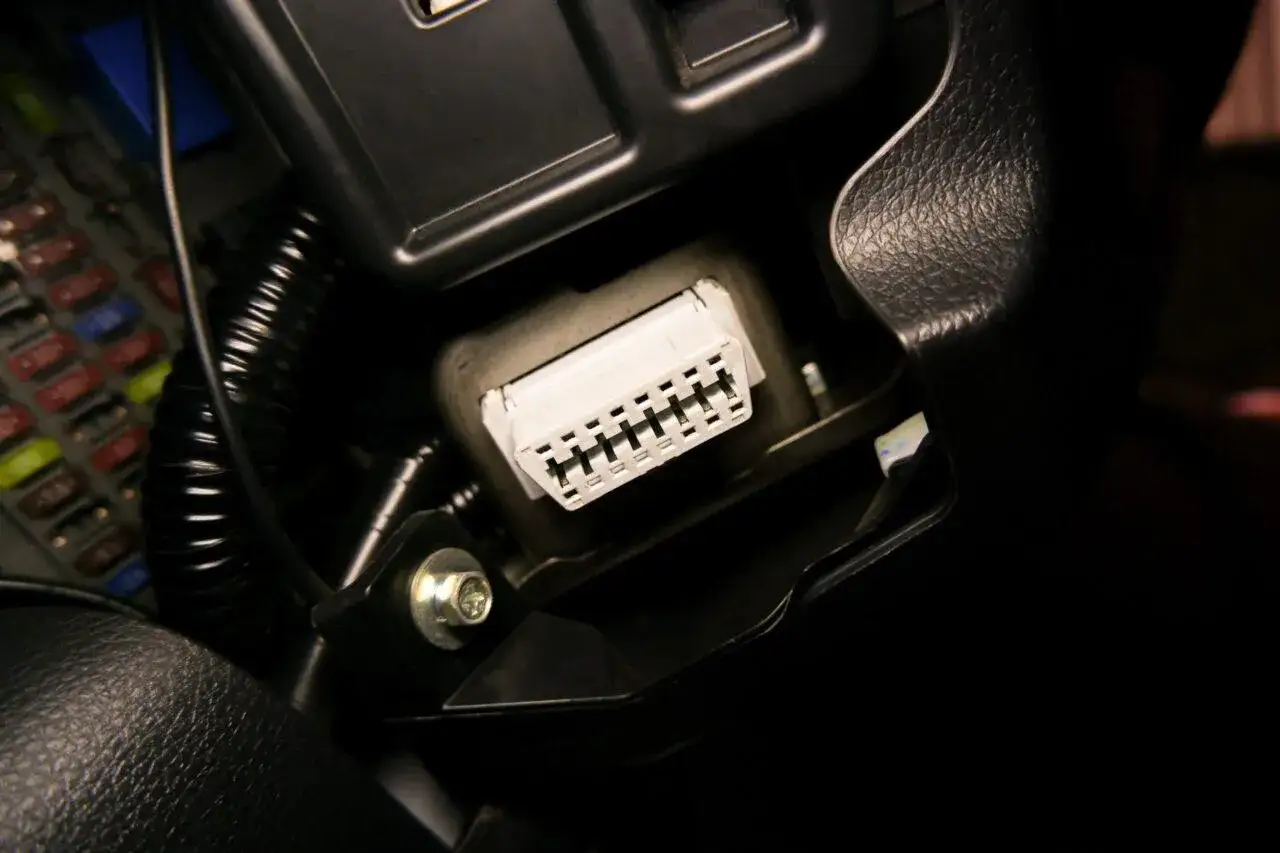 Connettore bianco con pin visibili, parte di una porta OBD per la diagnostica dell'auto.