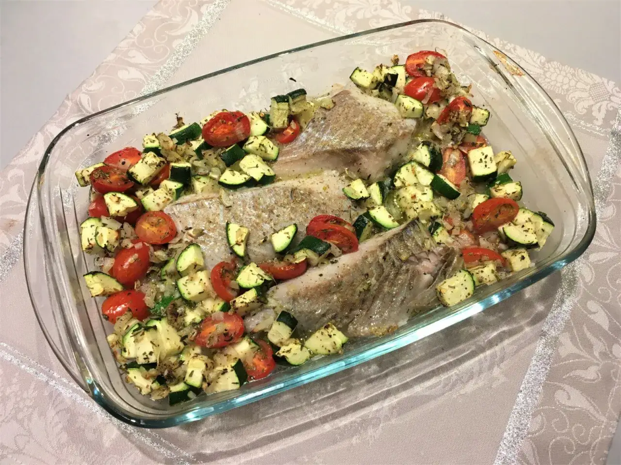 Filets de lieu noir au four avec tomates cerises et courgettes coupées en dés, assaisonnés d'herbes. Un plat sain et coloré prêt à être dégusté.