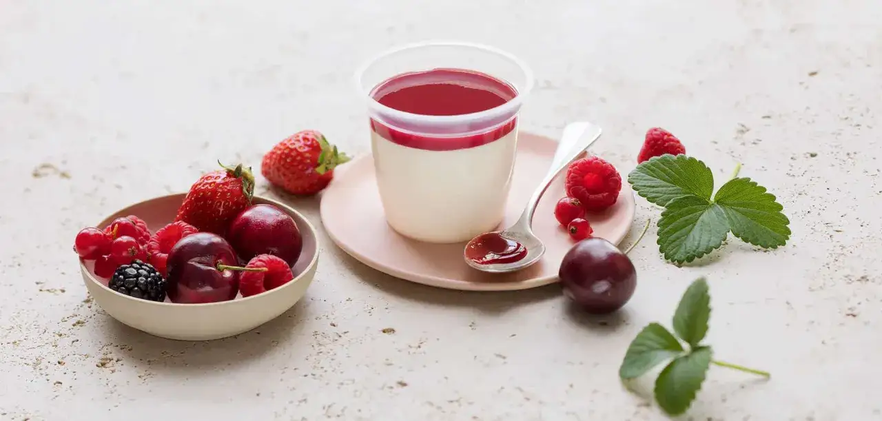 D&eacute;licieux panna cotta cr&eacute;meux, garni d'un coulis de fruits rouges. Autour, des fraises, framboises, groseilles, m&ucirc;res et cerises fra&icirc;ches.