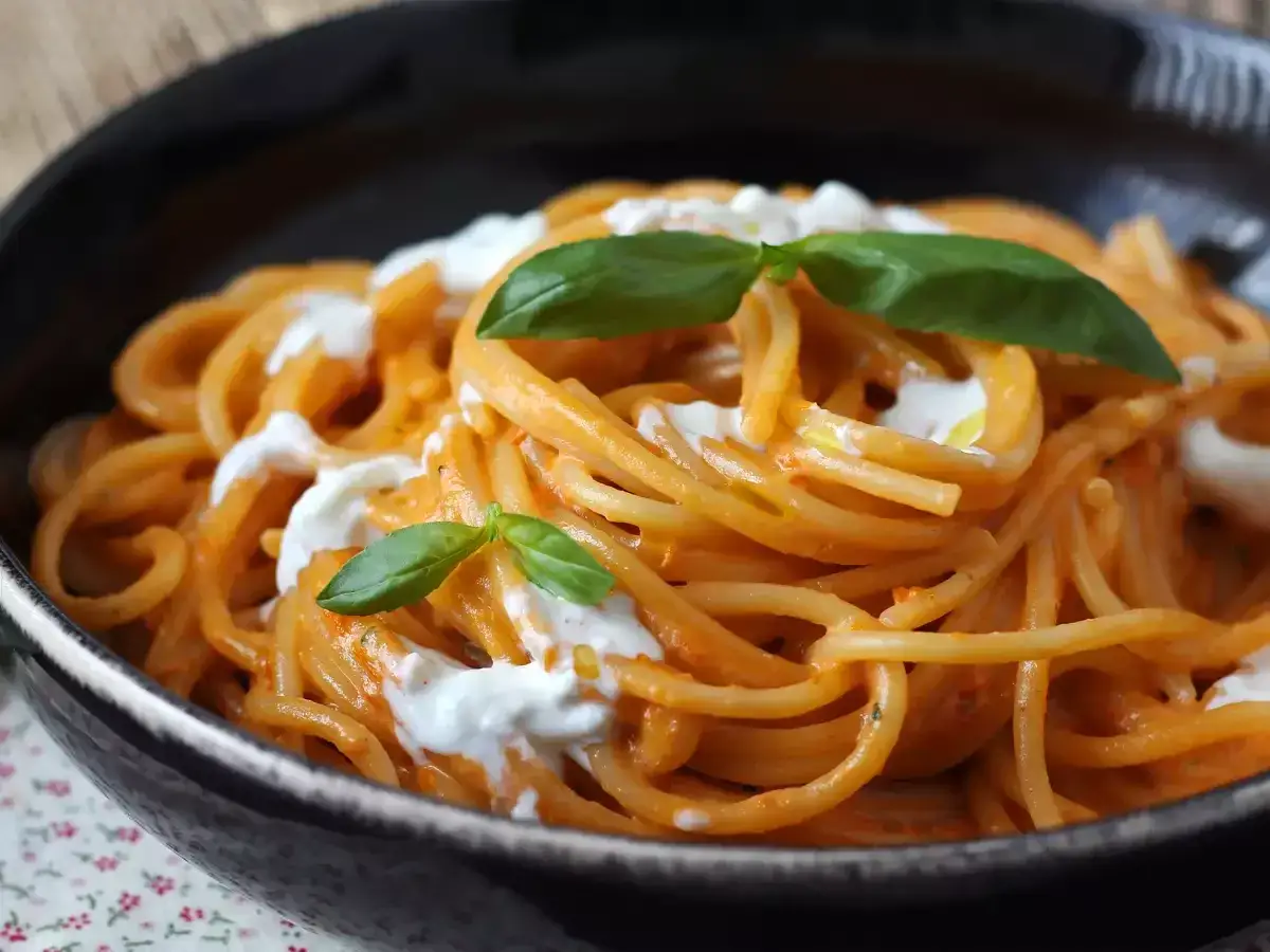 Spaghetti mit cremiger Tomatensoße und Burrata. Ein einfaches Gericht, das zeigt, wie vielseitig Burrata Rezepte sein können. Garniert mit frischem Basilikum.