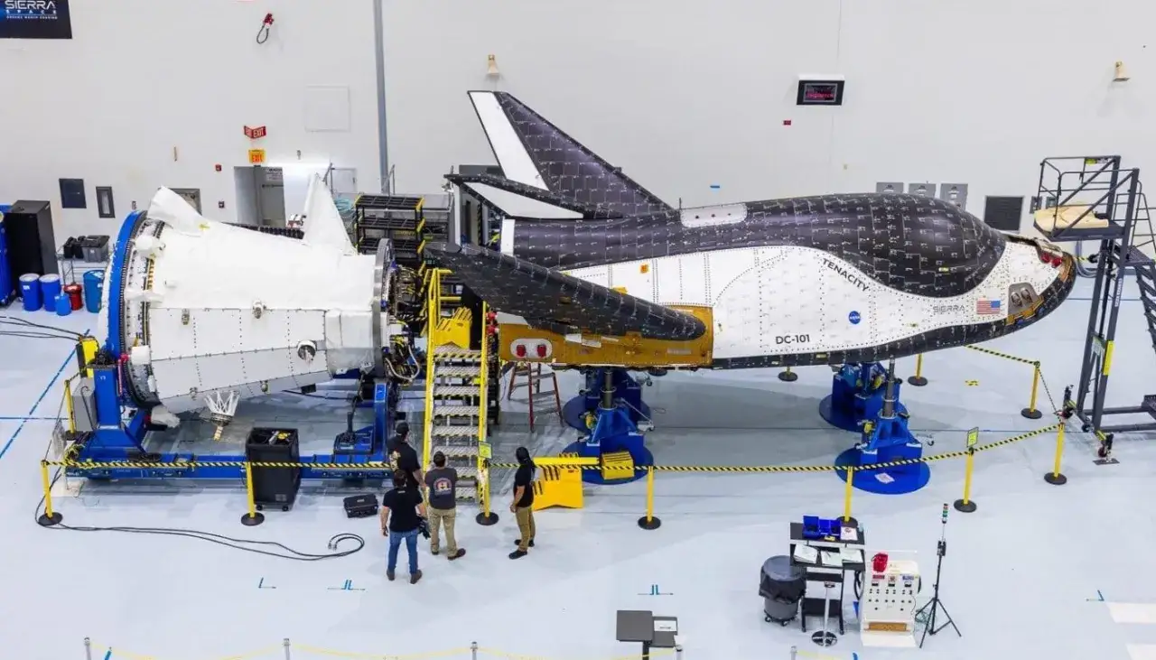 Dream chaser, kosmiczny pojazd DC-101, w hangarze Sierra Space. Zesp&oacute;ł technik&oacute;w pracuje nad jego montażem.
