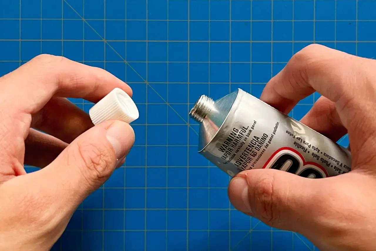 Mani che aprono un tubetto di colla, pronto per iniziare a riparare la ceramica.