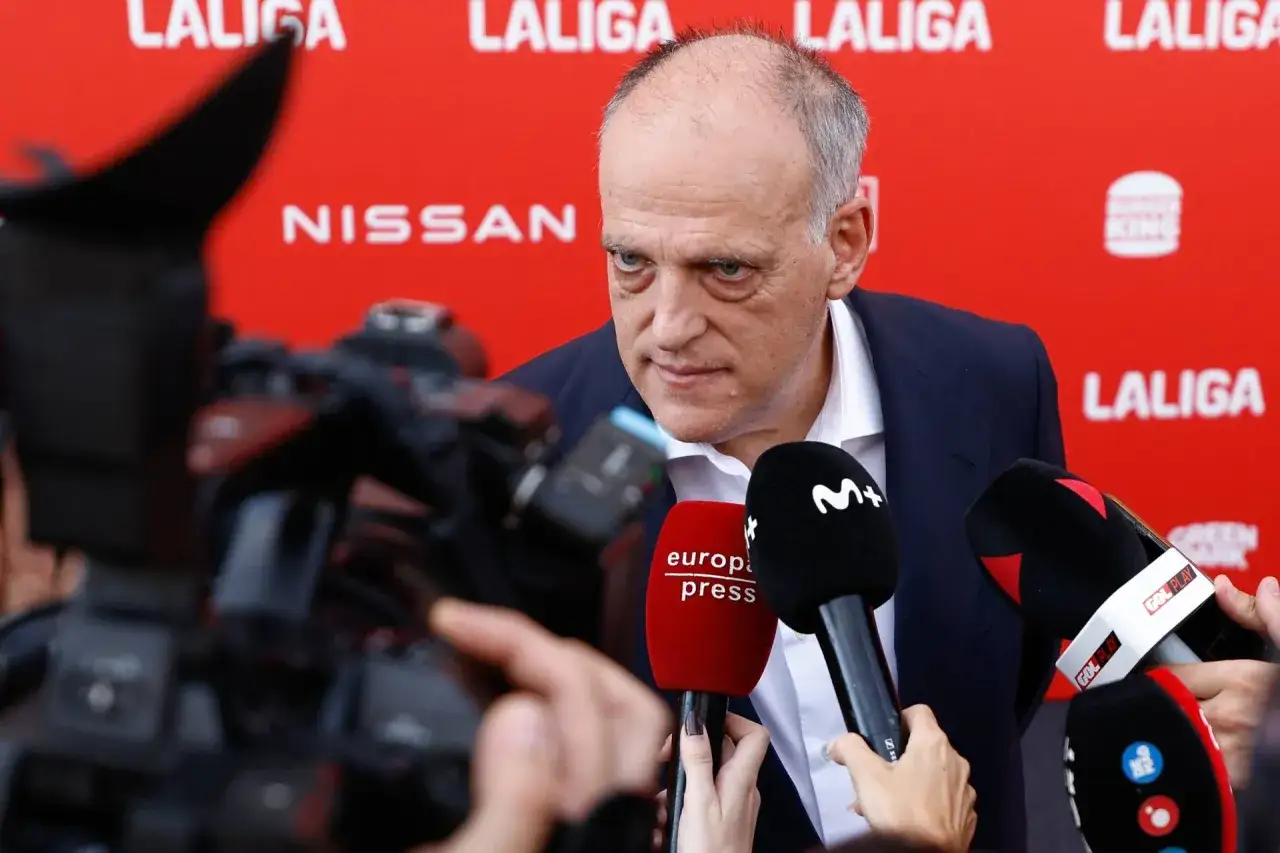 Javier Tebas, prezes La Liga, udziela wywiadu dziennikarzom na tle czerwonej ścianki z logotypami.