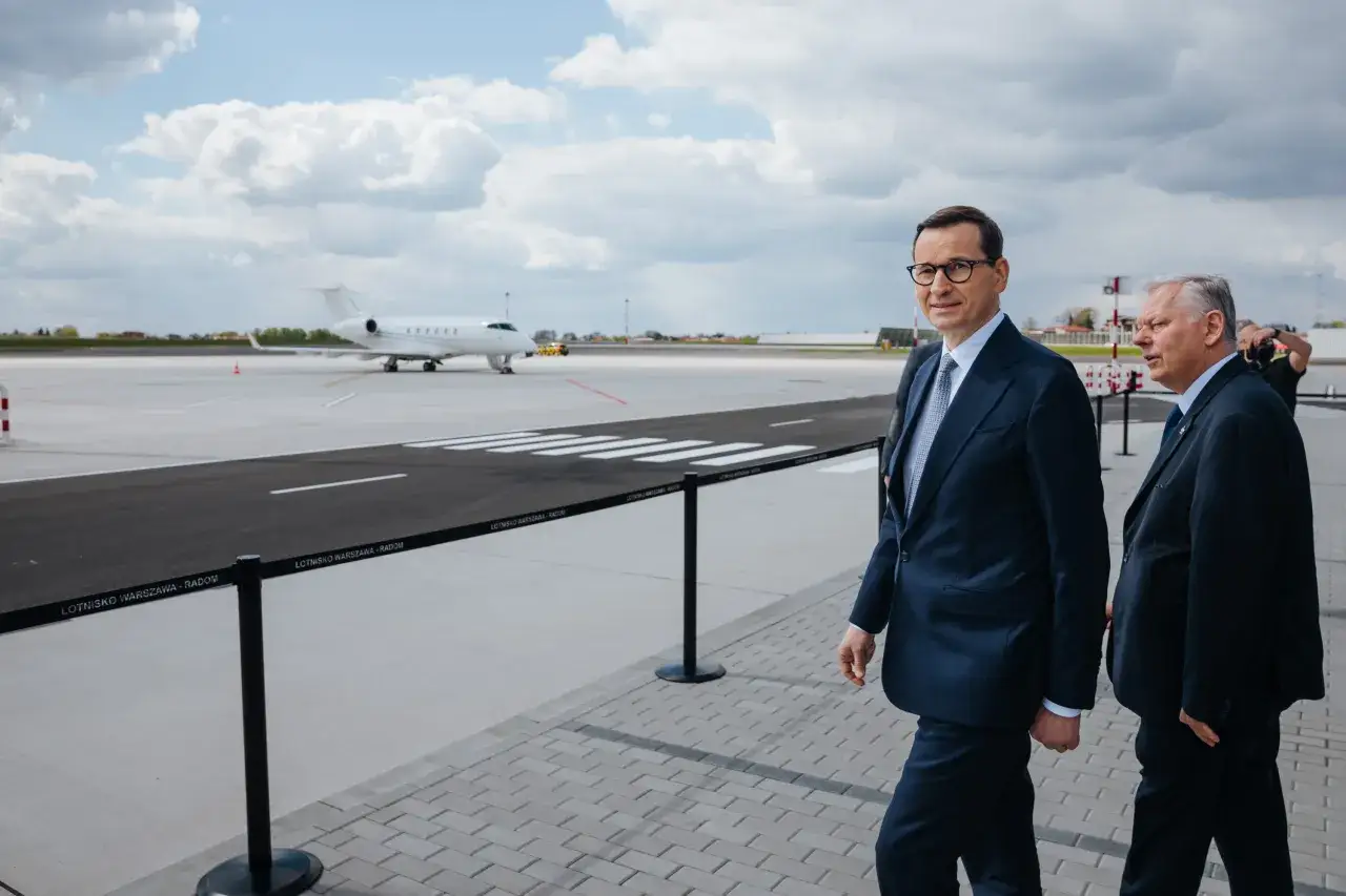 Dwóch mężczyzn w garniturach na płycie lotniska, w tle samolot. Pytanie o lotnisko Radom kiedy otwarcie nabiera sensu.