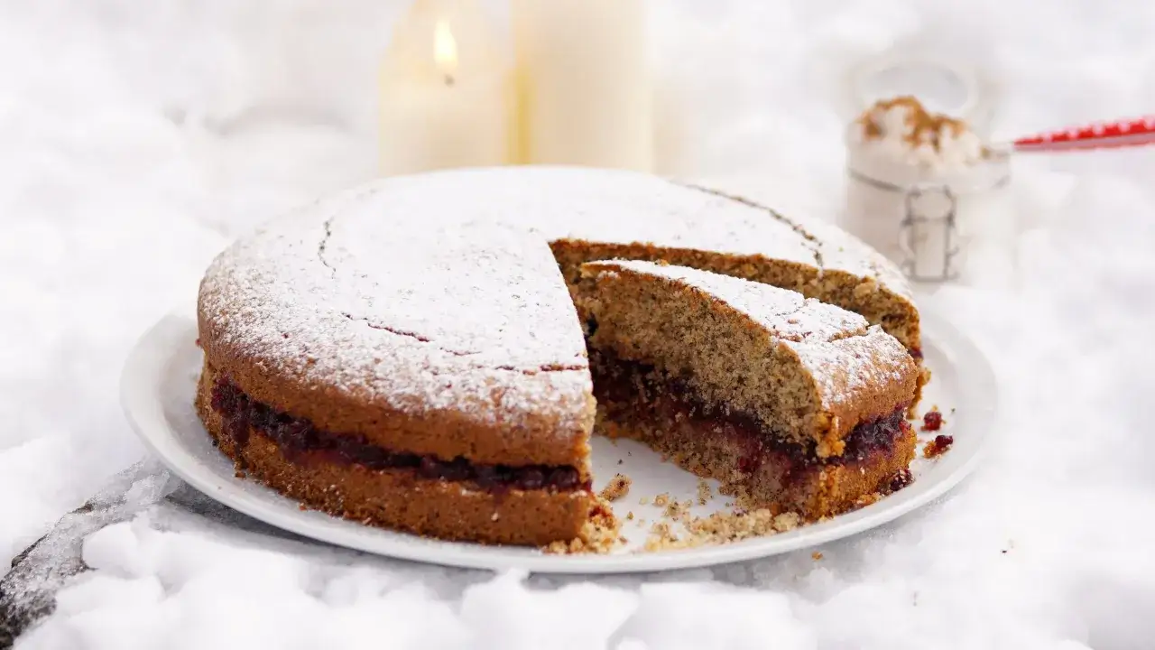 Torta grano saraceno trentino, soffice e ripiena di marmellata, cosparsa di zucchero a velo, su un letto di neve.