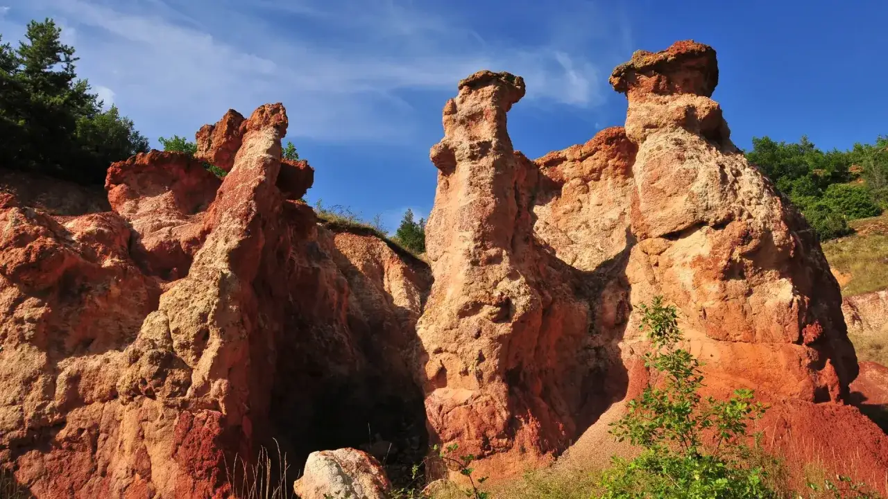 Formations rocheuses ocreuses, sculptées par le temps, évoquant des figures dans la vallée des saints boudes. Ciel bleu vif.