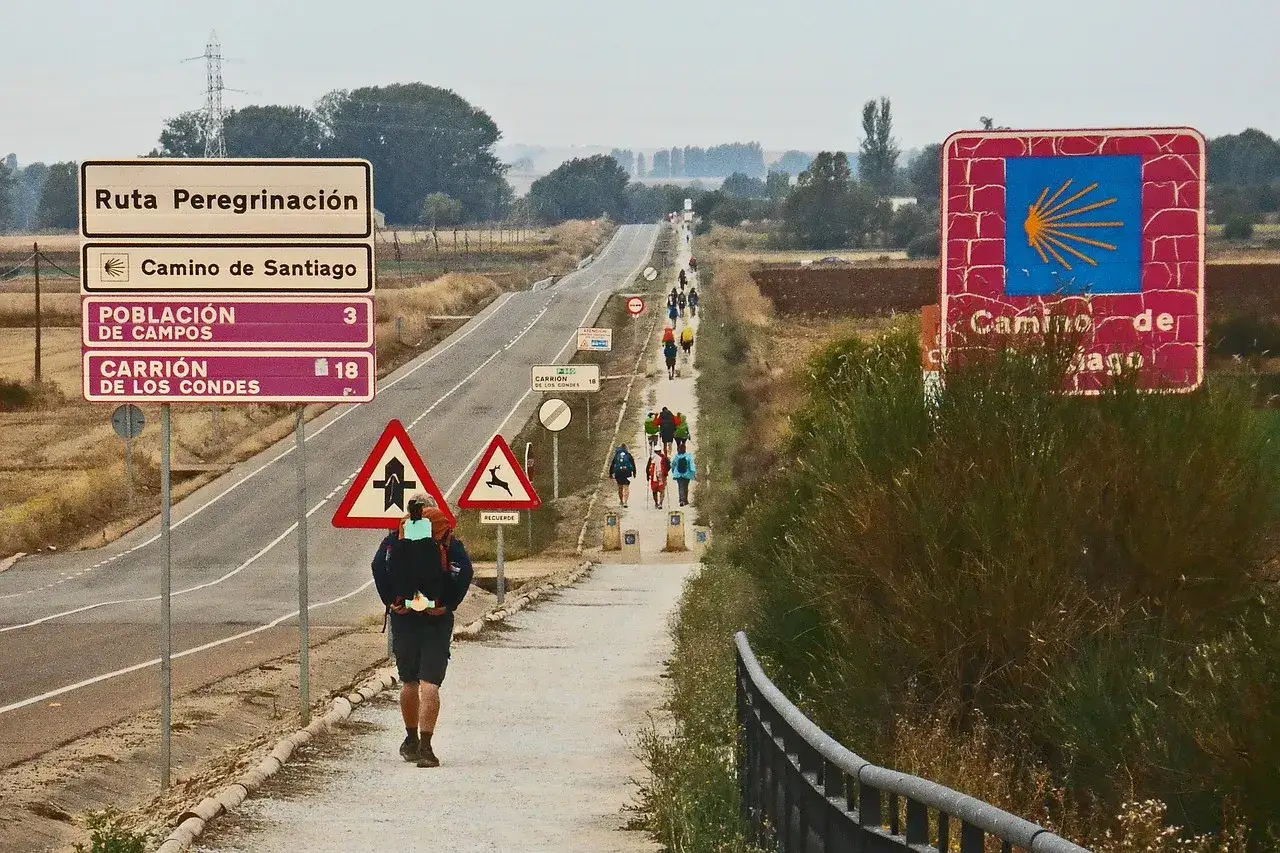 Pielgrzym idzie ścieżką Camino de Santiago. Znaki wskazują drogę do Santiago i odległości do miast. Święta w El Camino to czas wędrówki i refleksji.