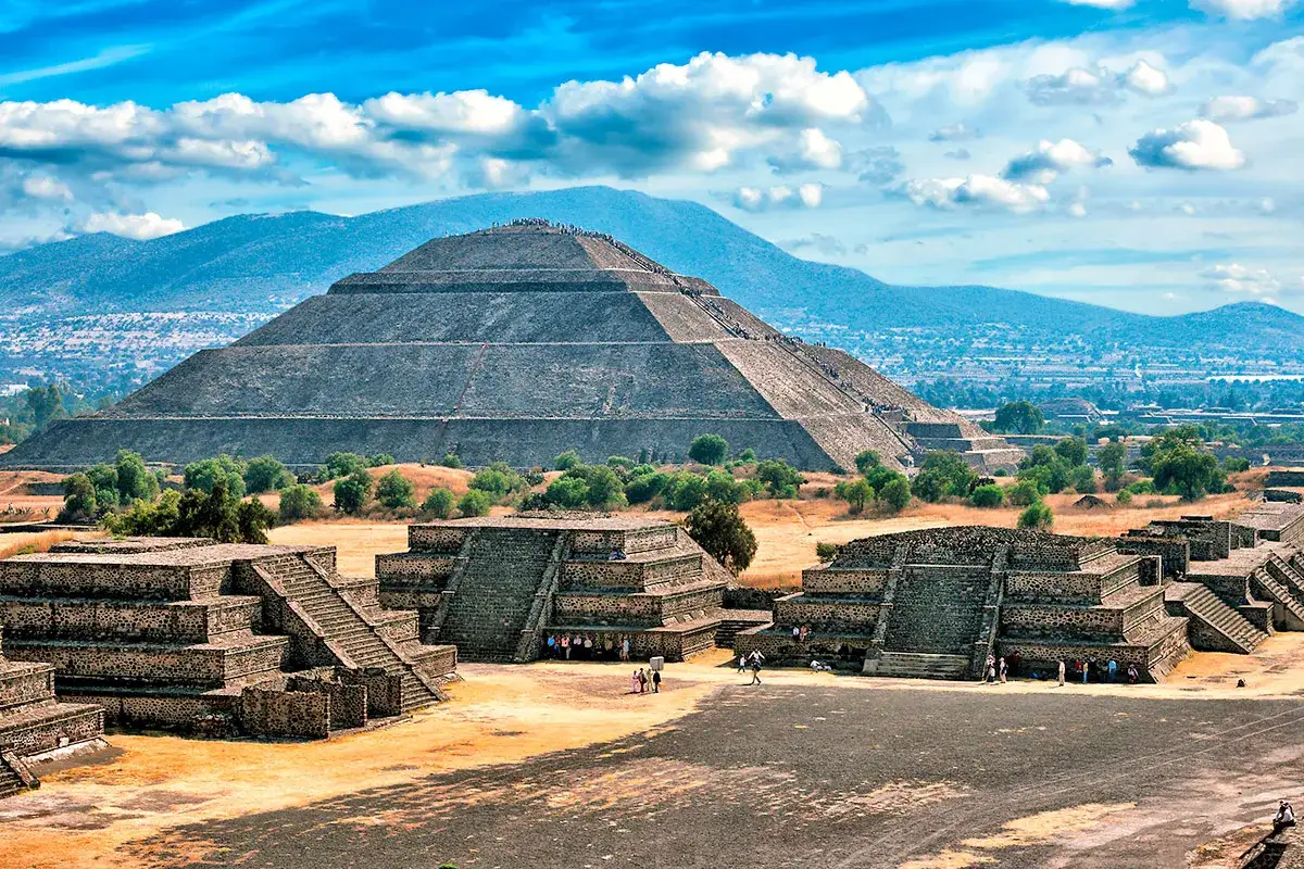 Majestätische mexikanische Pyramiden unter blauem Himmel. Die Sonne beleuchtet die antiken Stätten, während Besucher die Geschichte erkunden.