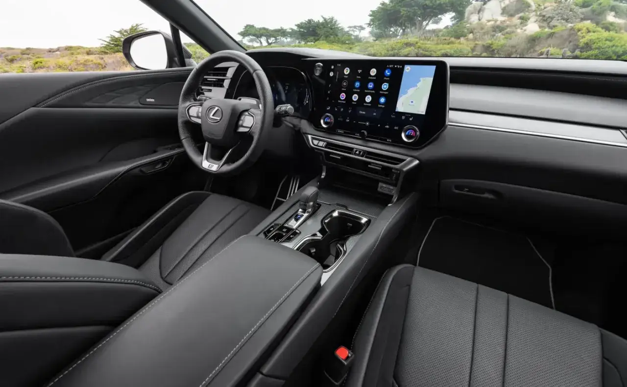 Wnętrze Lexus RX 500h: czarna skórzana tapicerka, duży ekran multimedialny z nawigacją, kierownica i konsola środkowa.
