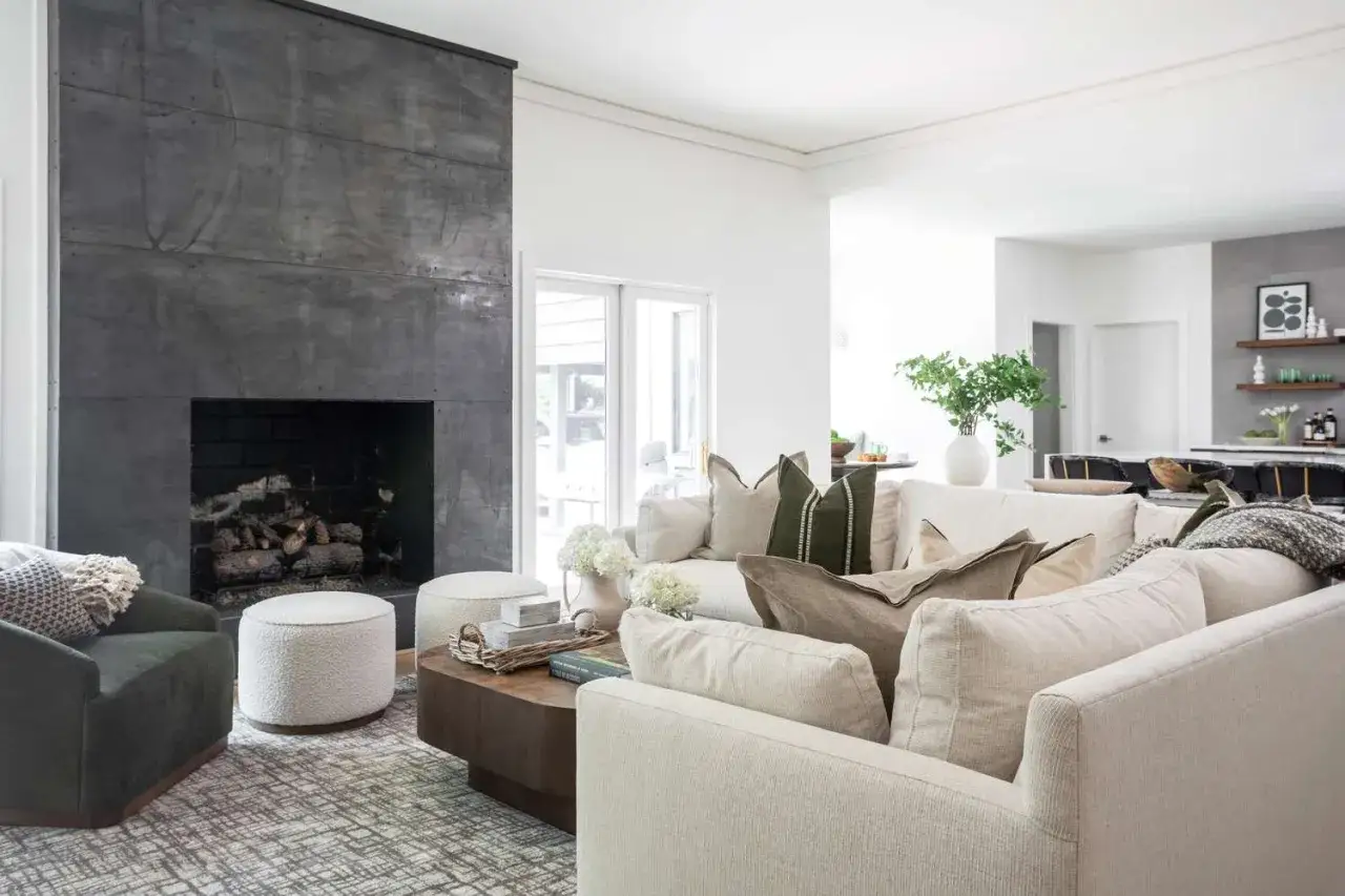 Modern family room ideas featuring a dark concrete fireplace, plush sectional, and cozy ottomans.