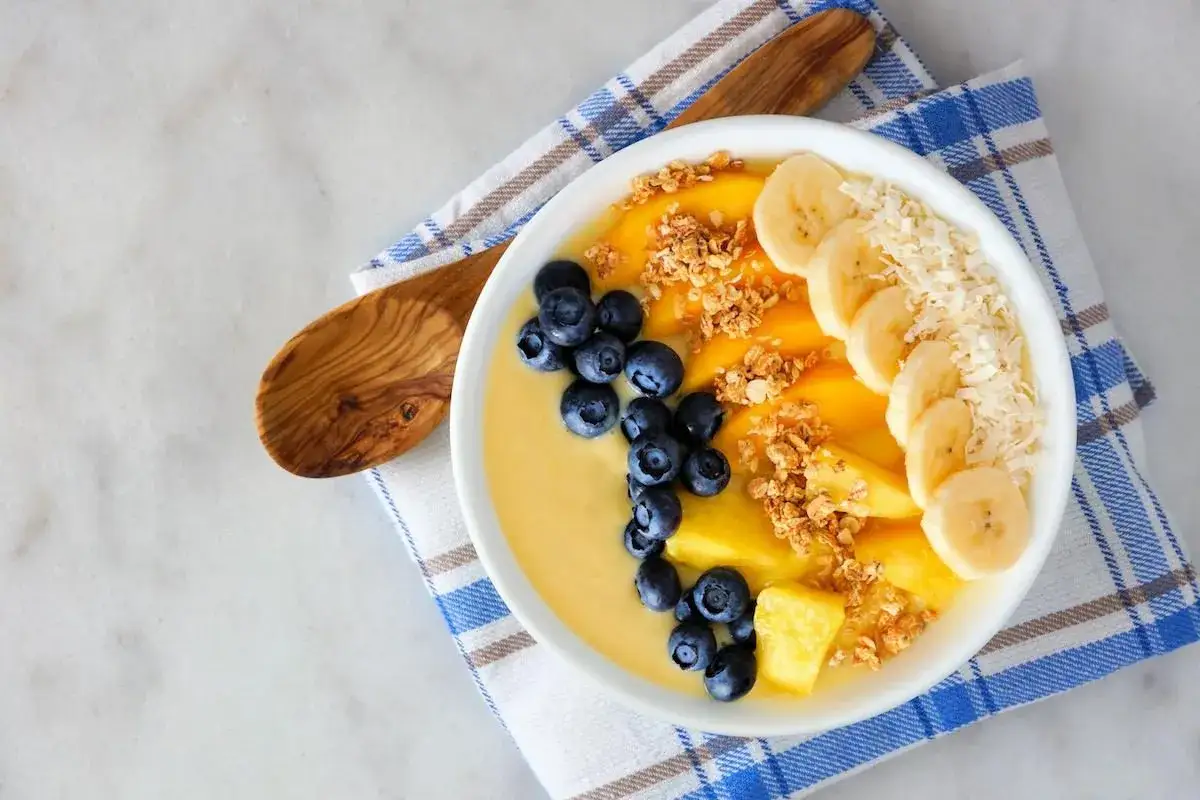 Kolorowy smoothie bowl z bananem, borówkami i granolą, przypominający wyglądem tradycyjny kisiel.