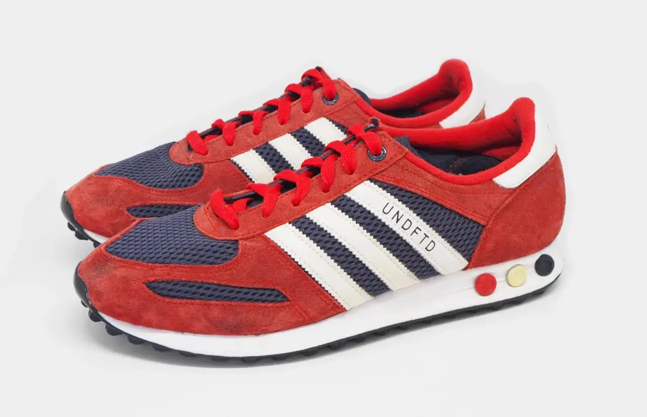 Czerwono-granatowe buty sportowe Adidas z białymi paskami i napisem UNDFTD. Prawdopodobnie najdroższe buty Adidas, jakie można znaleźć.