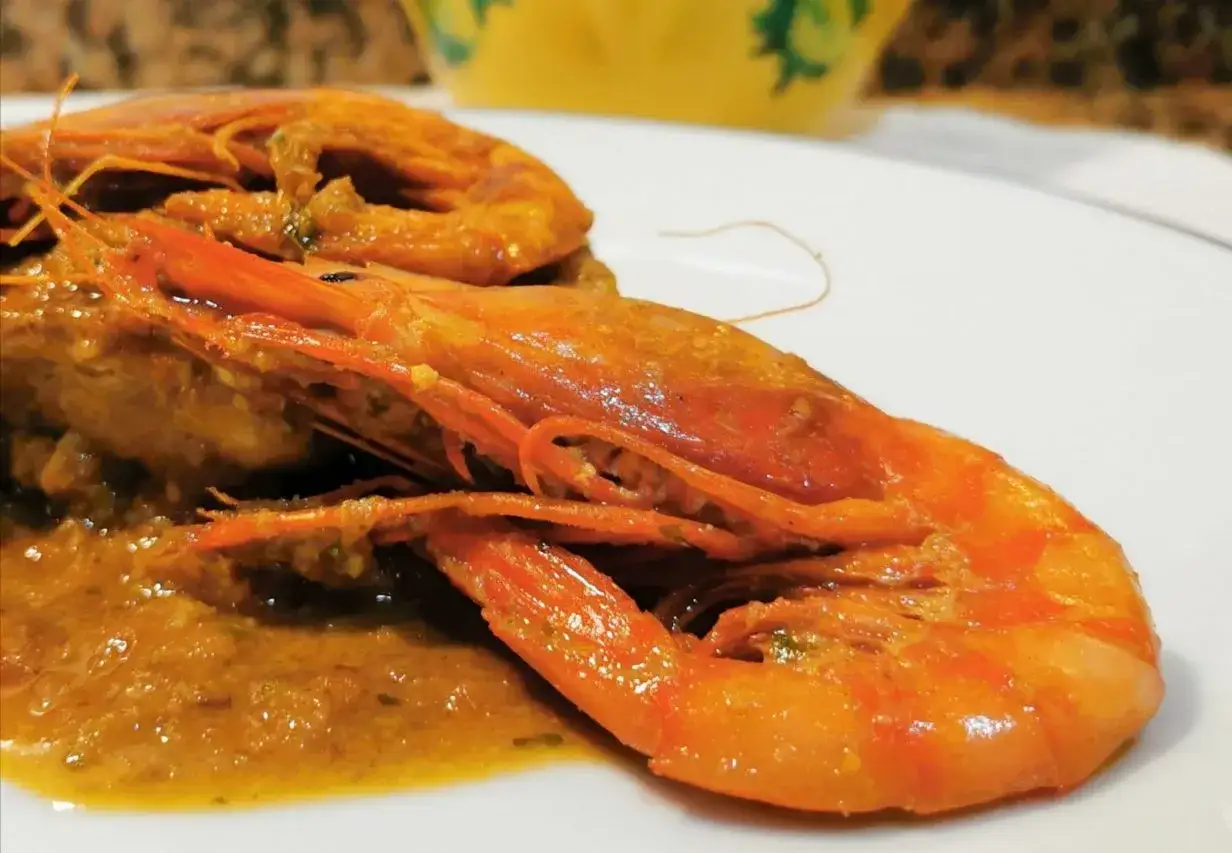 Delicioso pollo con gambas en una salsa dorada, servido en un plato blanco.