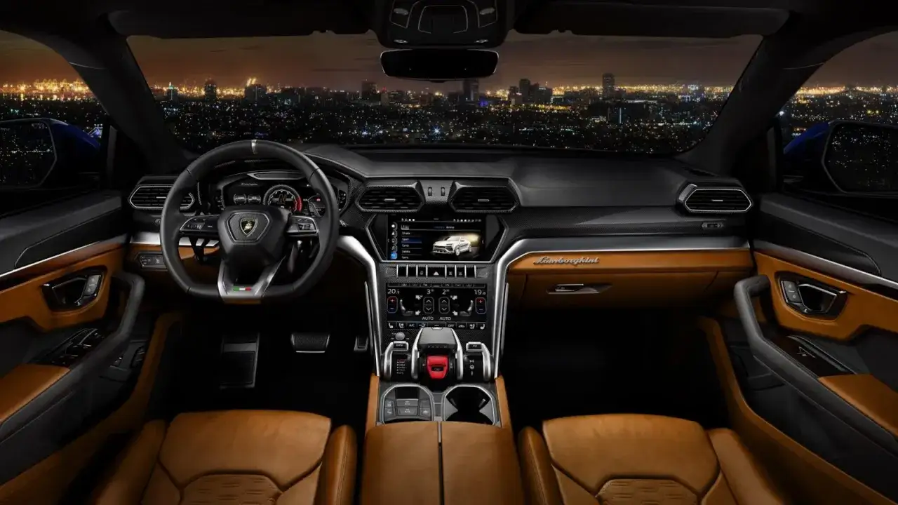 Wnętrze Lambo Urus z widokiem na nocne miasto. Skórzana tapicerka, sportowa kierownica i nowoczesny kokpit.