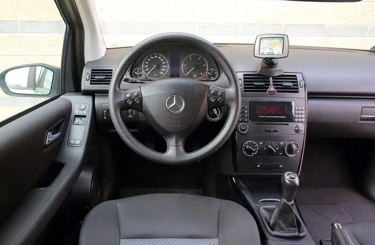 Wnętrze Mercedesa A Klasa 2001: kierownica, deska rozdzielcza z nawigacją, radio i dźwignia zmiany biegów.