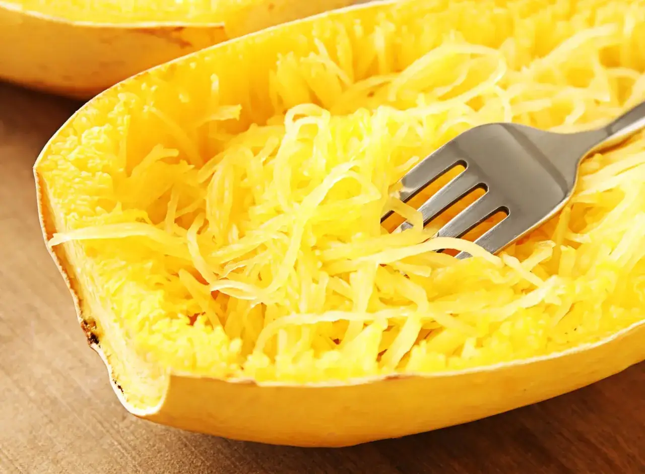Une fourchette sépare les filaments d'une courge spaghetti cuite, prête à être dégustée.