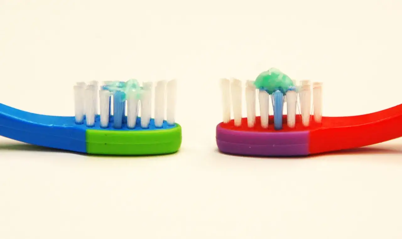 Spazzolini colorati con dentifricio al fluoruro di sodio pronti per l'igiene orale.