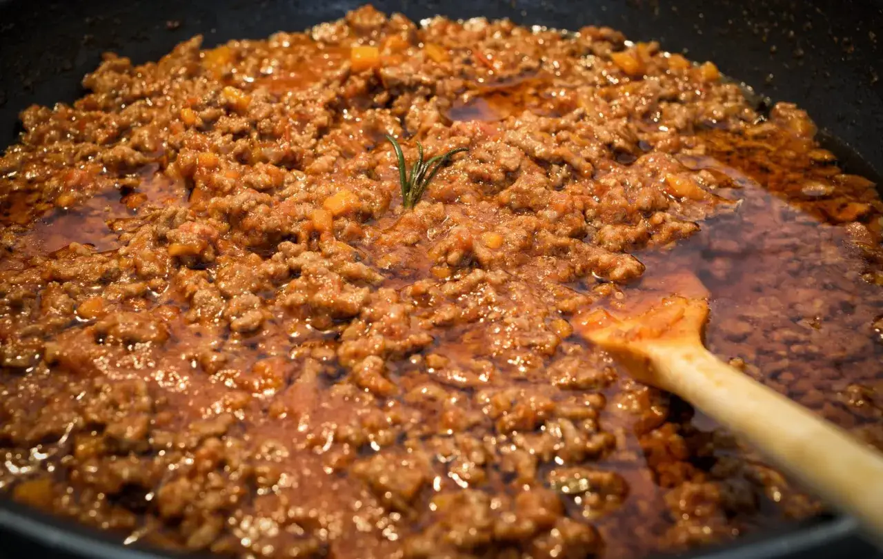 Un saporito rag&ugrave; di lepre cuoce lentamente in padella, con un rametto di rosmarino che profuma l'intingolo.