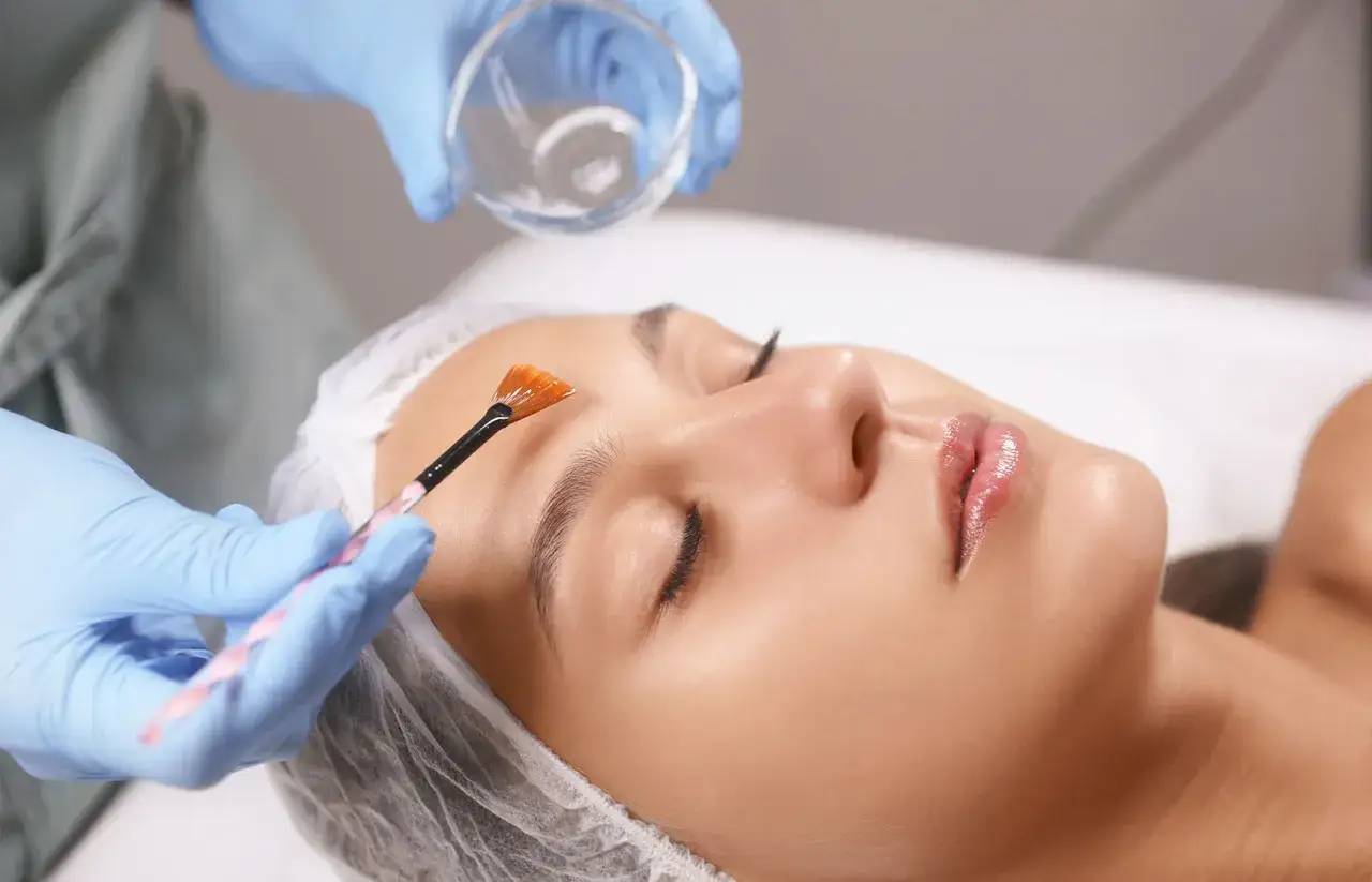 Applicazione di un trattamento PRX T33 viso con pennello su una donna sdraiata.