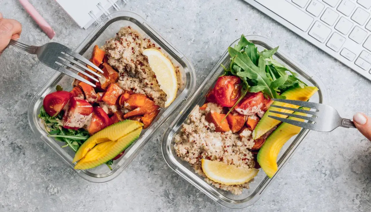 Två matlådor med quinoa, sötpotatis, tomater, avokado och ruccola. Perfekt för en 5:2 diet-lunch vid skrivbordet.