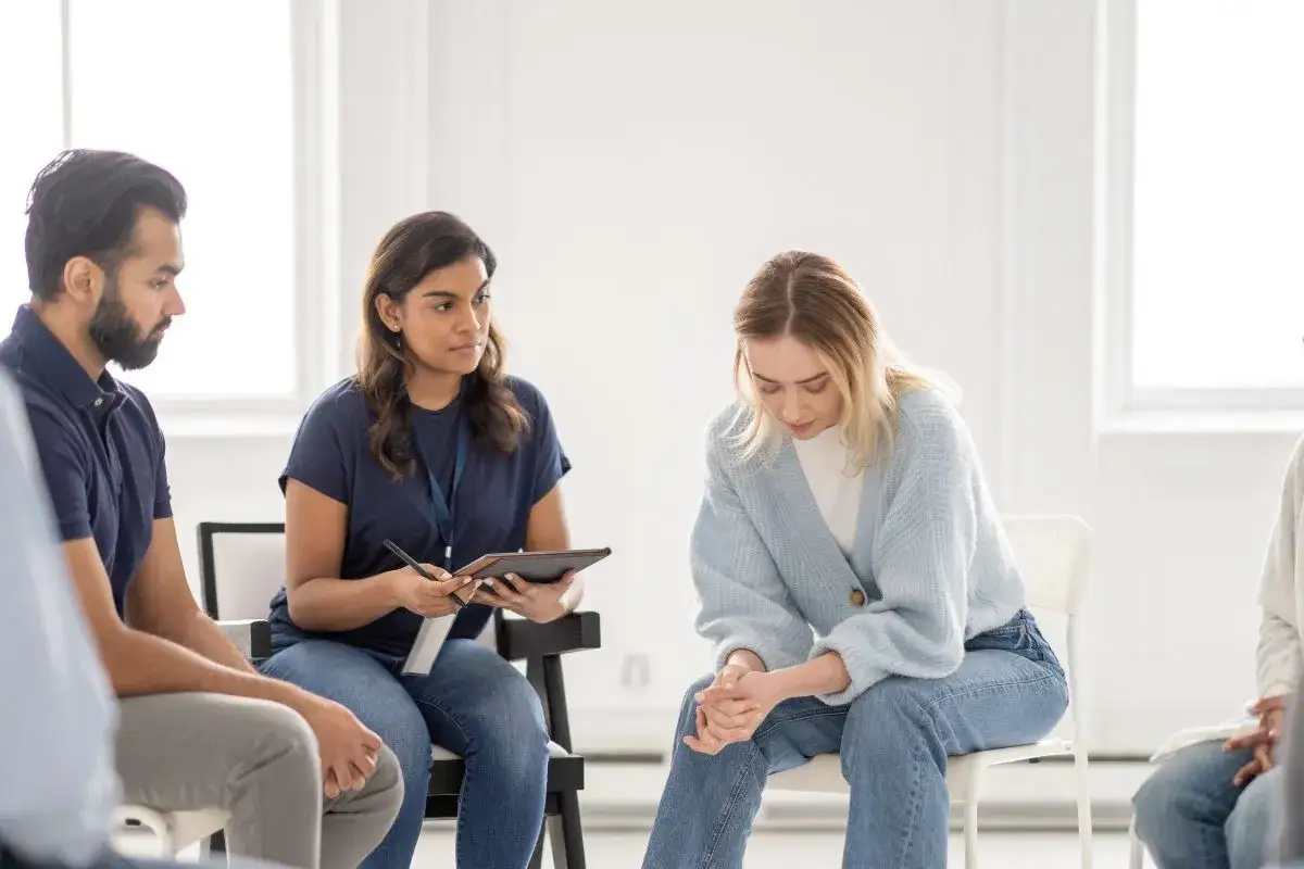 Grupa wsparcia, gdzie terapeutaka z notatkami obserwuje kobietę z oporem w psychoterapii.