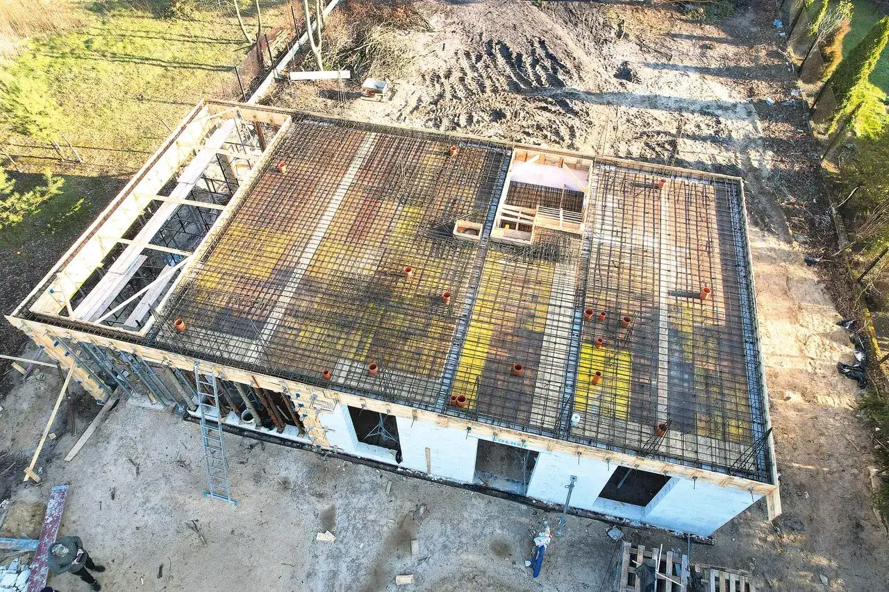Gotowy do zalania strop żelbetowy na budowie. Widoczna zbrojenie, szalunki i elementy instalacji.