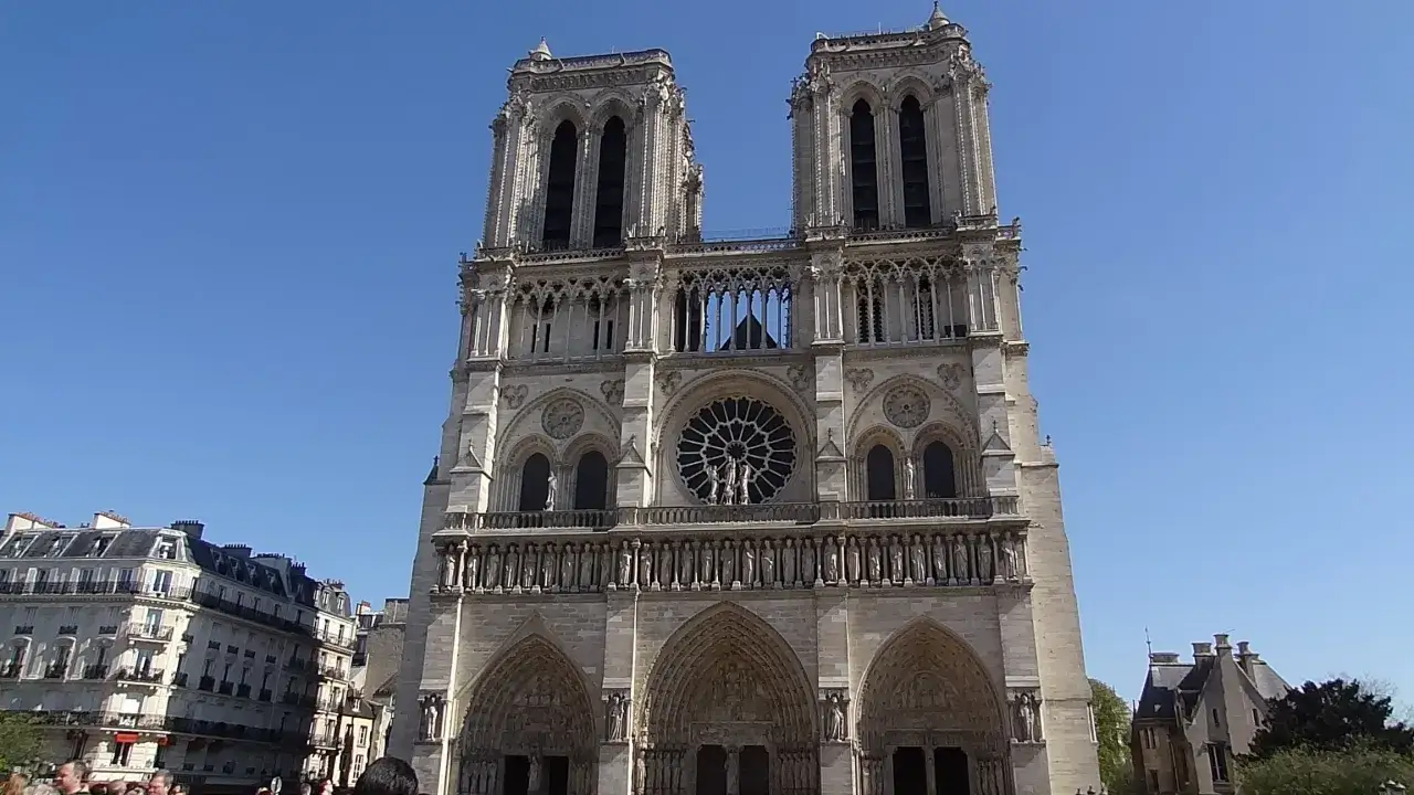 La majestuosa fachada de Notre Dame bajo un cielo azul. Disfruta de la entrada Notre Dame gratis y admira su arquitectura g&oacute;tica.