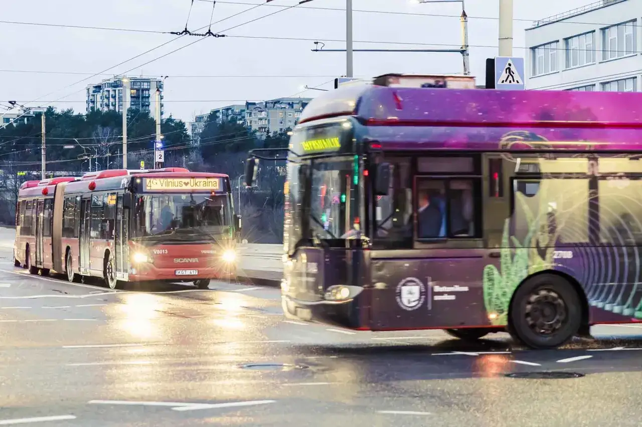 Dwa przegubowe autobusy, jeden czerwony z napisem 
