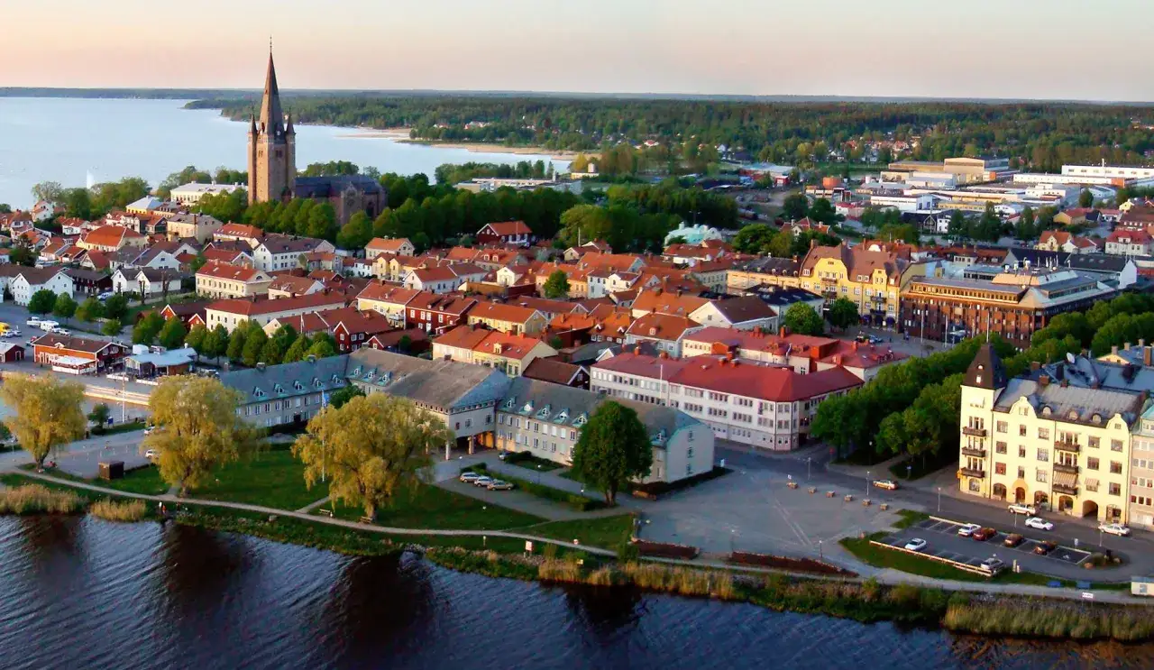 En vy &ouml;ver en stad vid en sj&ouml;, med en kyrka med h&ouml;gt torn. Husen har r&ouml;da tegeltak. Kanske &auml;r detta sveriges vackraste stad.