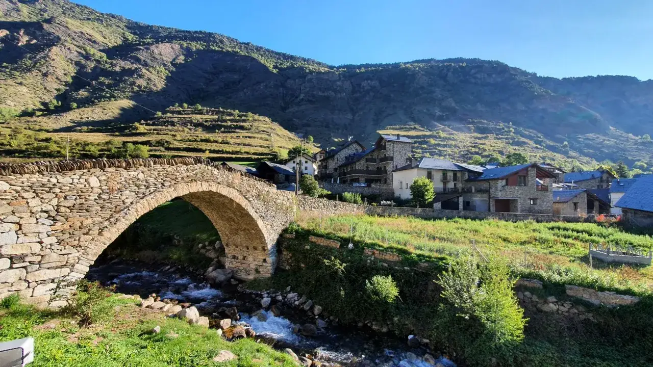 Puente de piedra y casas de monta&ntilde;a en el Pirineo de **Pallars Sobir&agrave;**.