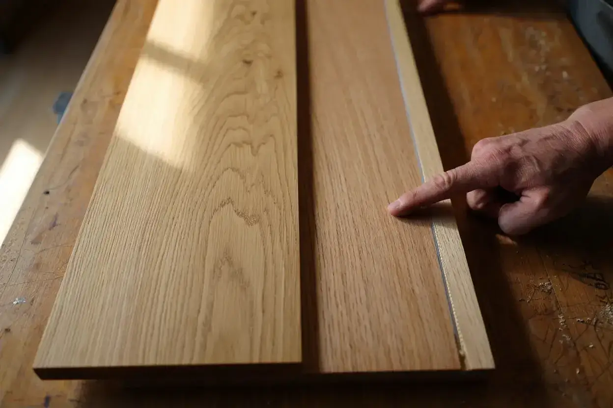 Main gauche pour reconna&icirc;tre bois meuble. Deux planches de ch&ecirc;ne sur un &eacute;tabli en bois, &eacute;clair&eacute;es par la lumi&egrave;re du soleil.
